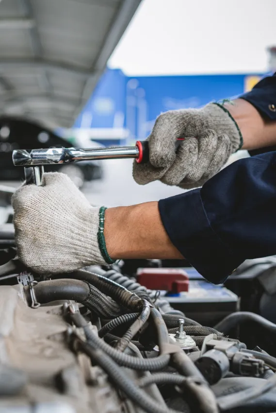 man wearing gloves working on a car engine